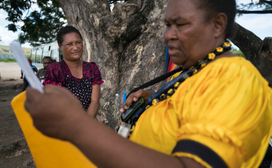 Tule looks at the papers she helped Cathy Umba (left) obtain, a protective order against her abusive former husband. Umba carries the papers with her at all times.