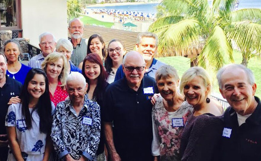 Group of KPBS Staff and Volunteers at appreciation luncheon; beach view behind them