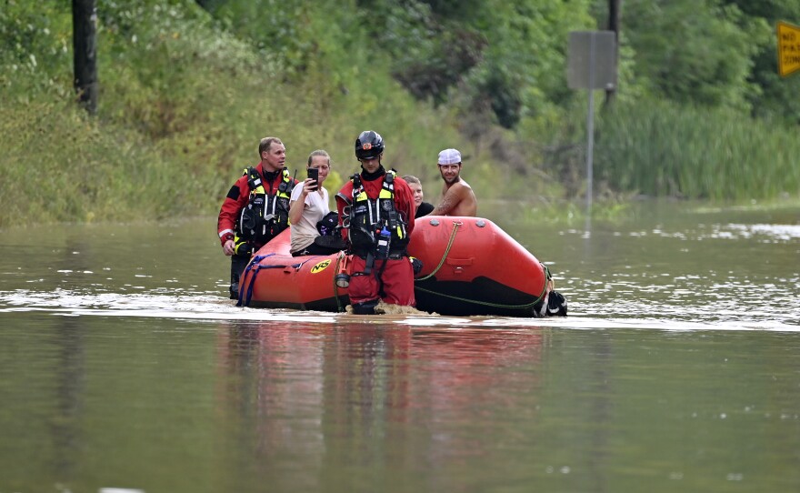 Members of the Winchester, Ky., Fire Department walk inflatable boats across flood waters over Ky. State Road 15 in Jackson to pick up people stranded by the floodwaters Thursday.