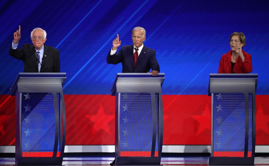 Sanders, Biden and Warren raise their hands during the debate.
