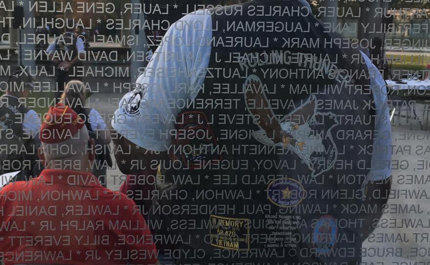 Participants in a "Rolling Thunder" POW/MIA ceremony are reflected in a Vietnam War memorial at Lejeune Memorial Gardens in Jacksonville, N.C.