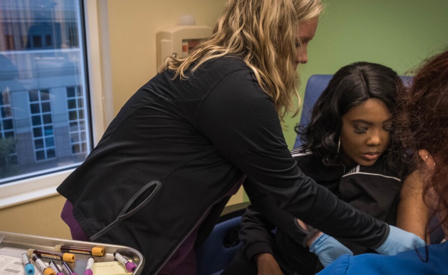 Nurses Bonnie Carroll (left) and Kayla Jordan draw vials of blood from Gray.