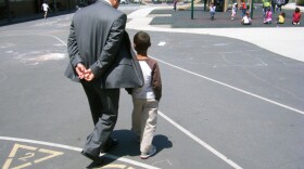 Cherokee Point Elementary School Principal Godwin Higa walks with a student on the playground in 2012.