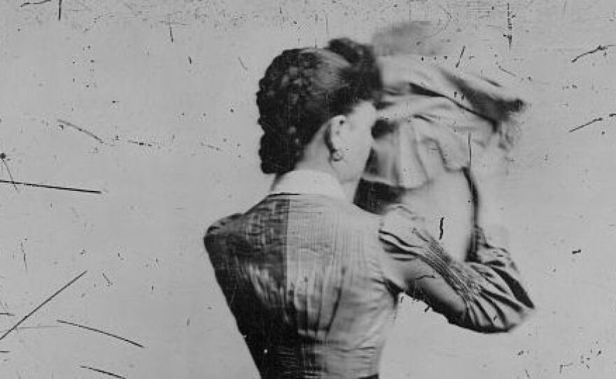 Woman holding a bonnet, with her back to camera, between 1880 and 1900.