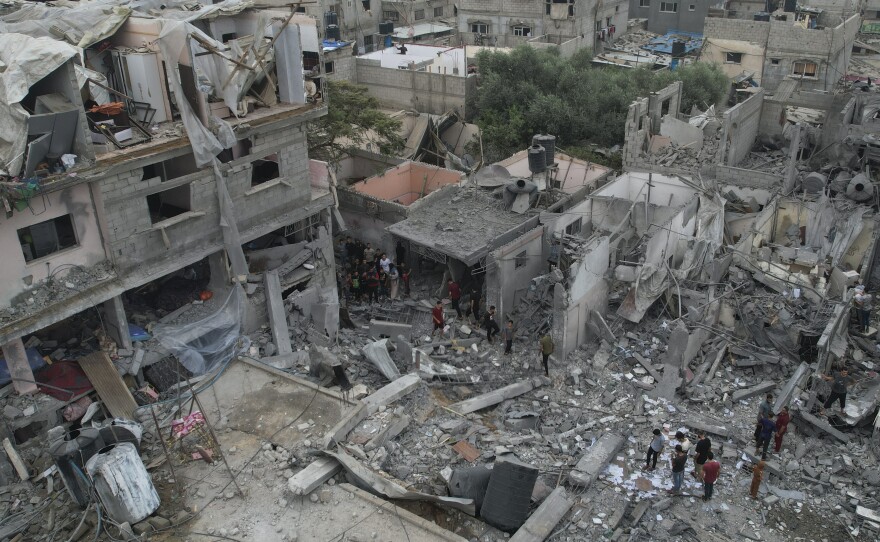 Palestinians walk about buildings destroyed in the Israeli bombardment in the Nusseirat refugee camp in the Gaza Strip on Sunday, Oct. 29, 2023.