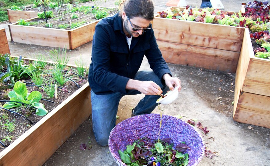 Los Angeles artist Michael Parker pours a dressing of lemon juice, olive oil, salt and pepper over edible flowers, herbs and greens. Parker also made this giant purple porcelain bowl.