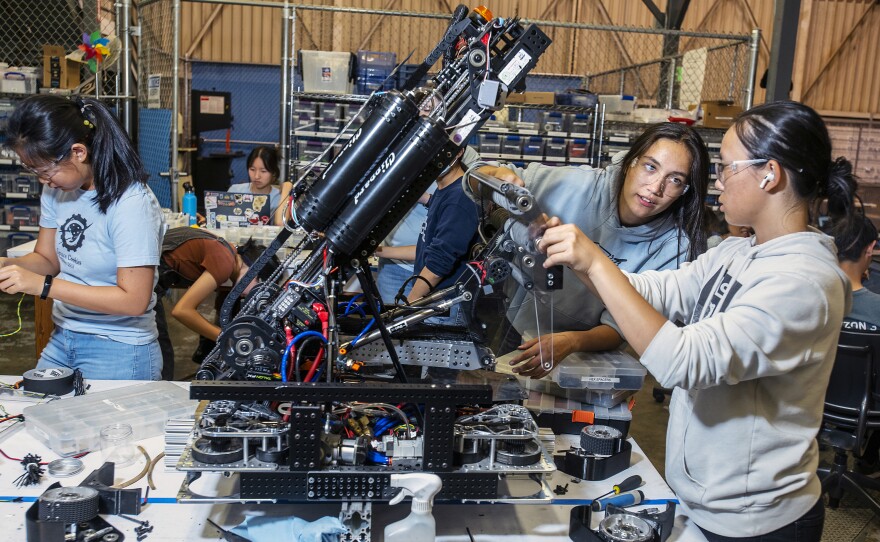 Claire Montegut (second from right), 16, and Anika Zhou (right), 17, are members of the Space Cookies, a <em>FIRST</em> Robotics Competition team composed of all Girl Scouts. Here they fix their robot's roller "claw" designed to pick up cones and cubes to score points.