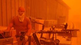 Navy aircraft mechanic checks on an explosive ordnance disposal robot during a dust storm August 8, 2005 at Camp Victory.