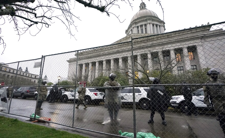 Members of the Washington National Guard stand near a fence surrounding the Capitol in Olympia, Wash., in anticipation of protests on Jan. 11, 2021.