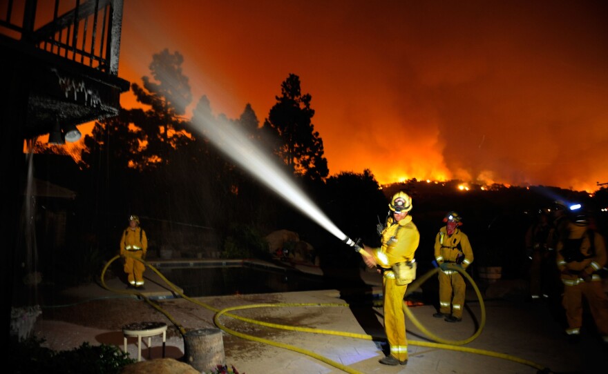 Firefighers spray white foam on a house as flames approach homes in the Jesusita Fire on May 7, 2009 in the foothills above Santa Barbara, California.  Photo by Kevork Djansezian/Getty Images