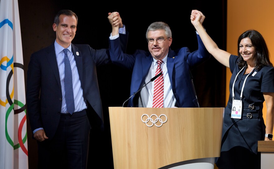 Los Angeles Mayor Eric Garcetti (from left), IOC President Thomas Bach and Paris Mayor Anne Hidalgo raise hands Tuesday in Lausanne, Switzerland, after the IOC voted the cities can work out a deal to host the 2024 and 2028 Olympics.