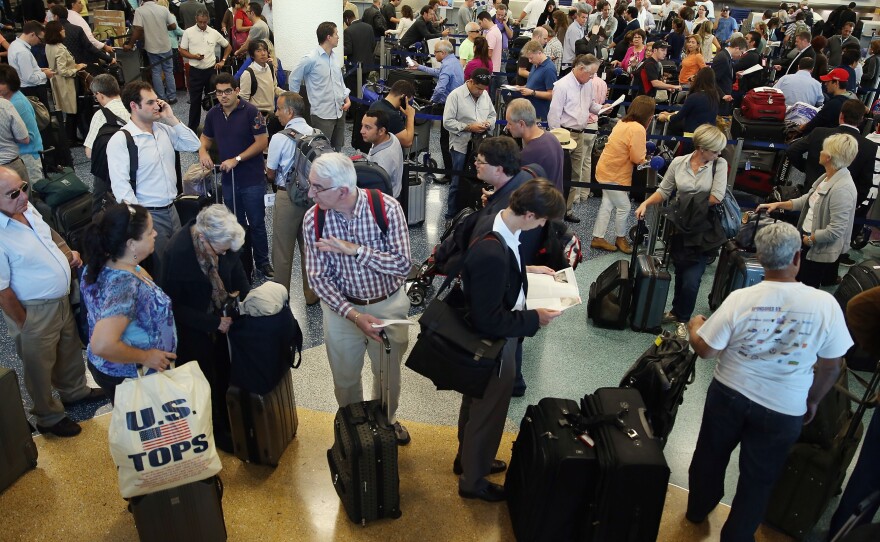 American Airlines passengers wait in line for a flight at Miami International Airport on Tuesday.