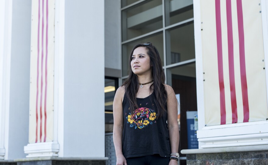 Thao Ha, who grew up in Houston and now teaches in California, at a Vietnamese store with the red stripes of the South Vietnamese flag on the wall behind her in Houston.