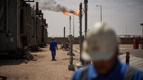 Workers walk in the Zubair oil field, whose operations have being reduced since the start of the Iran war, near Basra, Iraq, March 28.