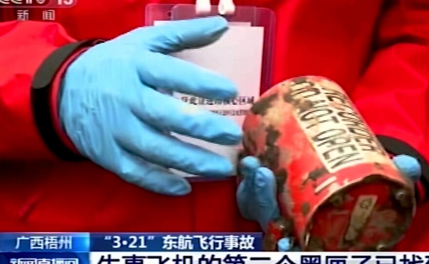 In this image taken from video footage run by China's CCTV, a search and rescue worker holds the second orange-colored "black box" recorder recovered at the China Eastern flight crash site.