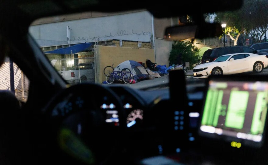 A San Diego Police Department patrol vehicle drives past an encampment in downtown San Diego on March 22, 2024.