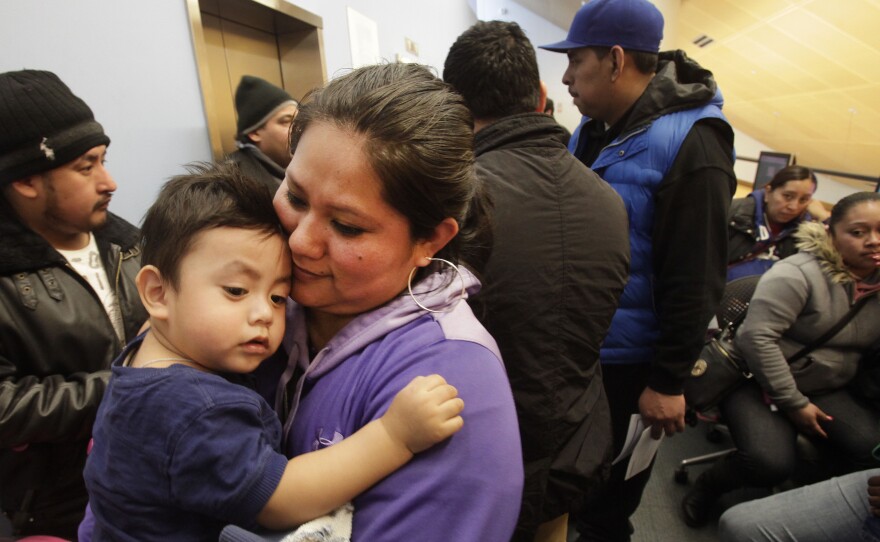 Veronica Ramirez holds her 15-month-old son, Lora, as she waits in line Monday to apply for a new municipal identification card at the Bronx Library Center in New York.