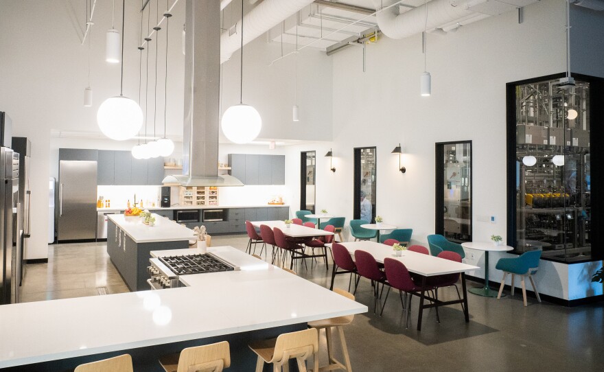 The lobby at Upside Foods is a dining area where one can see meat being produced through windows in a wall.