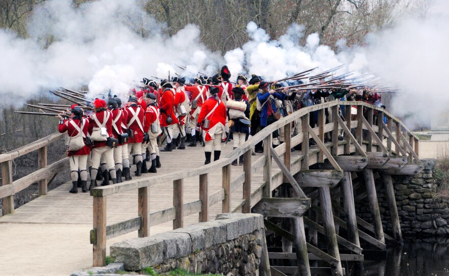 Minute Men and British reenactors fire a musket salute off the North Bridge at Minute Man National Historical Park.
