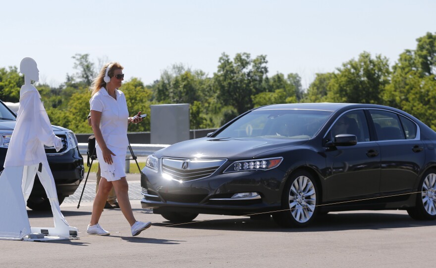 A pedestrian crosses in front of a vehicle as part of a demonstration at Mcity on July 20, on the University of Michigan campus in Ann Arbor, Mich.