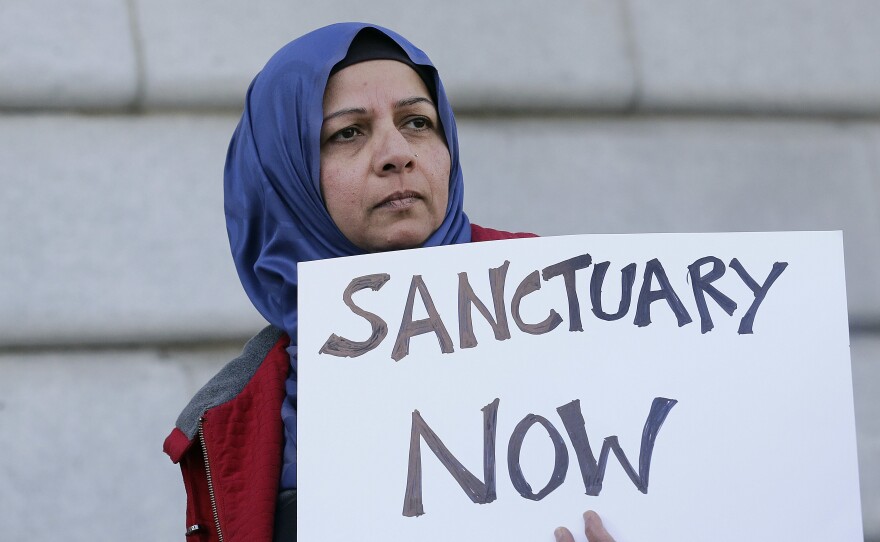 Protester Moina Shaiq holds a sign at a rally outside of City Hall in San Francisco. On Tuesday, a federal judge blocked a Trump administration order to withhold funding from sanctuary communities.