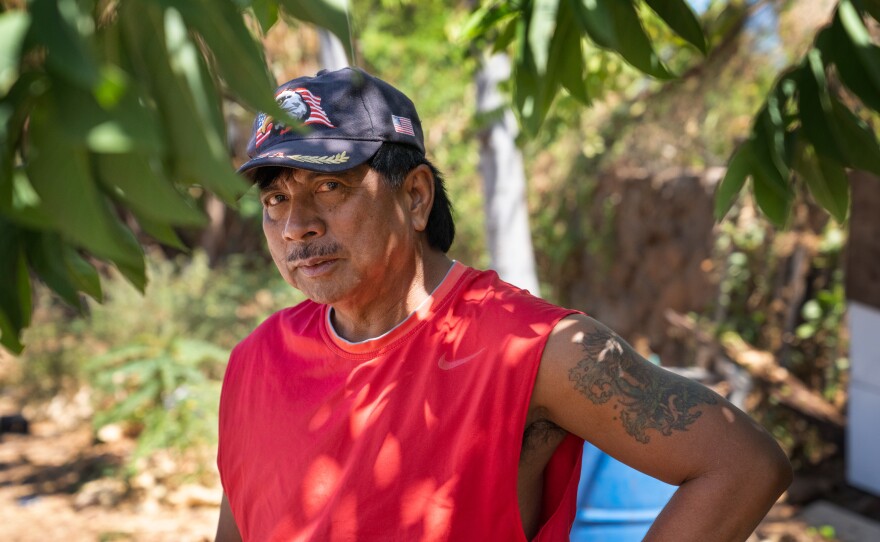 Andres stands in the shade of a papaya tree he planted in the yard around the house.