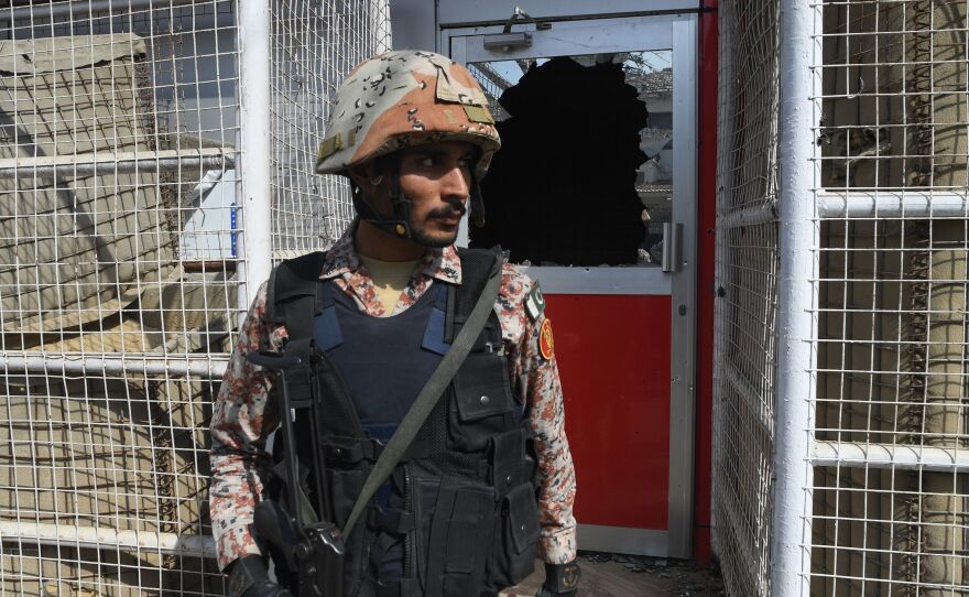 A Pakistani ranger stands in front of a damaged gate at the Chinese consulate after an attack in Karachi on Friday.