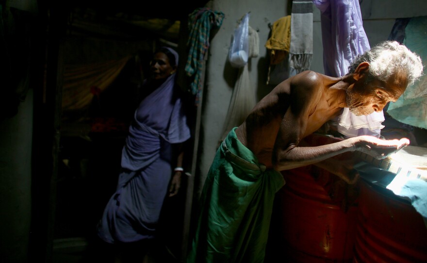 Debendra Tarek, 80, inspects a handful of salt-resistant rice in his home on the tidal island of Ghoramara, which is shrinking quickly because of climate change.