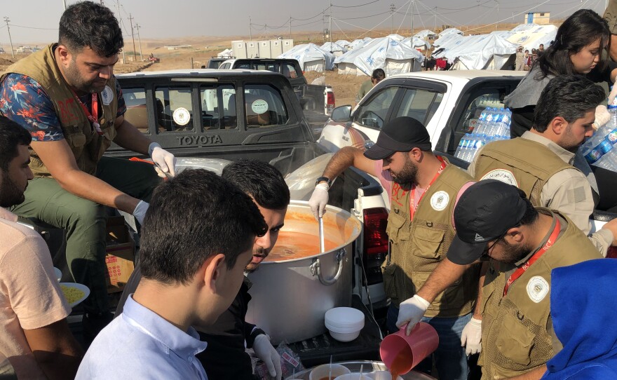 Aid workers dish up rice and stew to refugees at the Gawilan camp in northern Iraq. The camp has accommodated nearly 2,000 new arrivals in the past month.