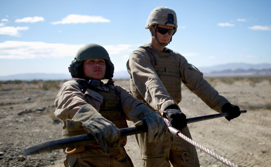 Marine Lance Cpl. Paula Pineda (left) and Cpl. Ryan Donk pull out a winch cable for a vehicle towing exercise.