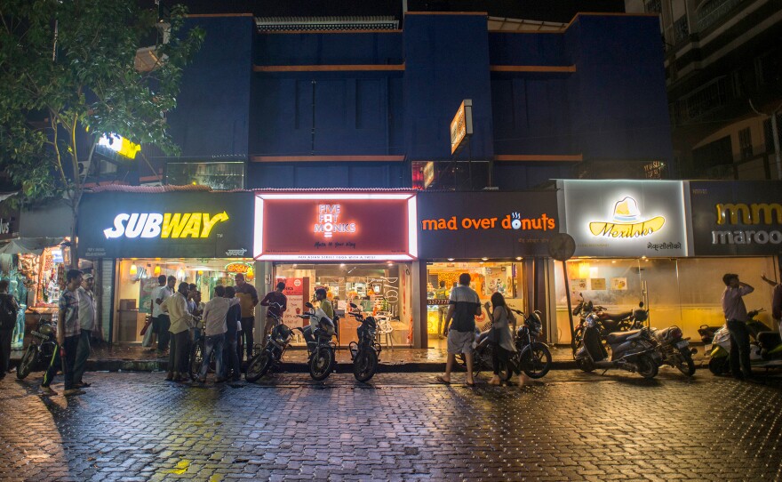 Pedestrians visit fast-food restaurants in Mumbai, India. Rapid urbanization in many developing countries is driving the demand for fast foods and highly processed, packaged foods.