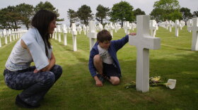 A mother and son visit a grave at Normandy American Cemetery.