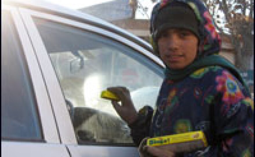 Malayeh, 11, tries to hawk gum to a driver on a busy street in Kabul.