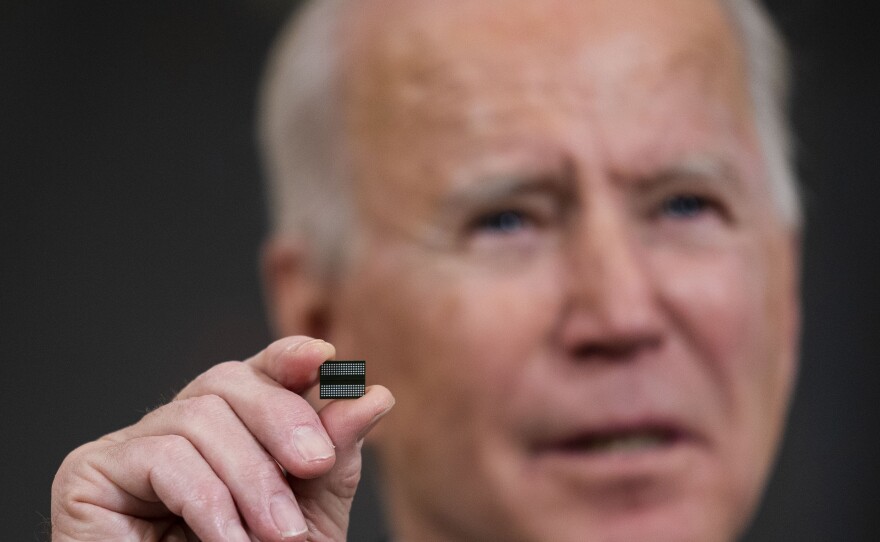 President Biden holds a semiconductor during remarks before signing an Executive Order on the economy at the White House on Feb. 24. On Monday, senior members of his team will meet with leaders across various industries to discuss a shortage of semi-conductors.