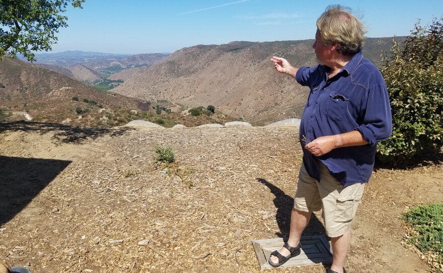 Pete Beauregard points to the valley below his Ramona home where the Witch Creek Fire burned in 2007, Aug. 26, 2019.