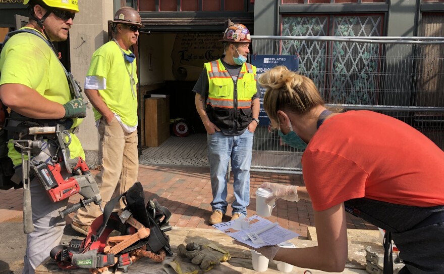 Lauren Moran, who's been helping her extended family as they reopen Cornwall's, brings menus and free coffees over to a construction crew working next door, hoping to stir up business, at a time when customers are scarce.