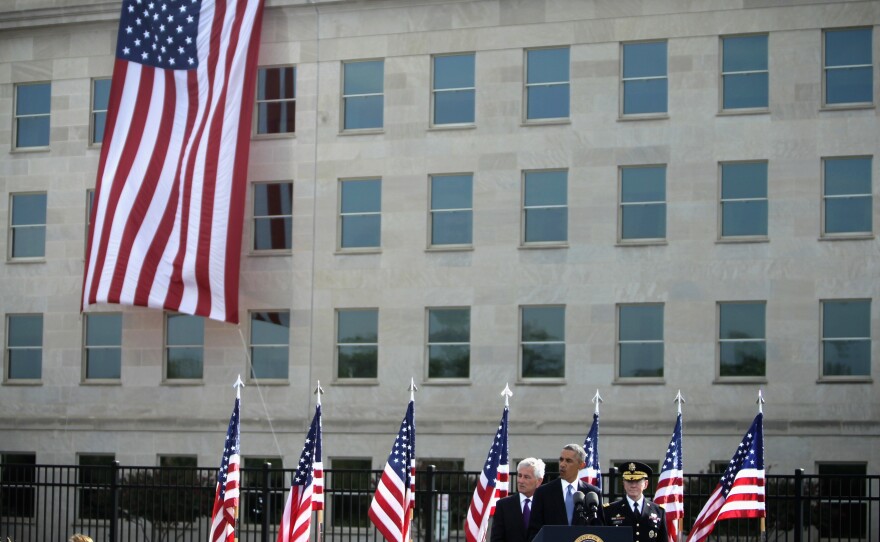 U.S. President Barack Obama (2nd L) speaks as Secretary of Defense Chuck Hagel (L) and Chairman of the Joint Chiefs Gen. Martin Dempsey (R) listen during a ceremony to mark the 13th anniversary of the 9/11 terrorists attacks at the Pentagon Memorial September 11, 2014 in front of the Pentagon in Arlington, Virginia.