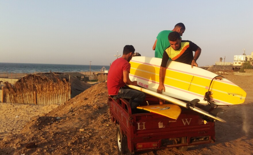 Members of the Gaza Surf Club drive a tuk-tuk down to the beach, to carry their surfboards.