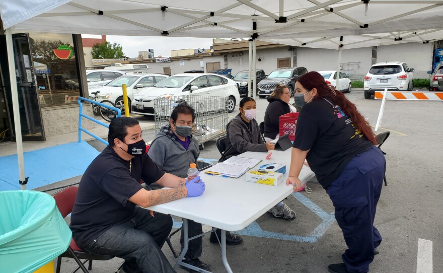 People at the Community Through Hope warehouse help check in people experiencing homelessness to get free showers and other services, Feb. 1, 2022.