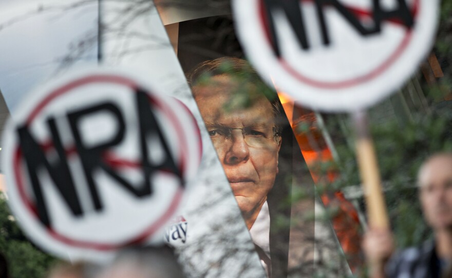 Protesters gather beneath a banner featuring Wayne LaPierre, CEO of the National Rifle Association, during a rally outside the NRA's annual meeting in Dallas in May. When the NRA told doctors to "stay in their lane" instead of weighing in on gun policies, Dr. Joseph Sakran sprang into action and created a Twitter account to encourage medical professionals to share their stories.