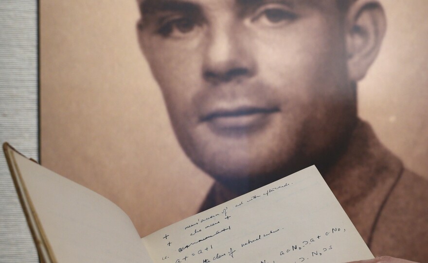 A page from the notebook of World War II code-breaking genius Alan Turing is displayed along with his portrait. The 56-page manuscript sold for more than $1 million Monday.