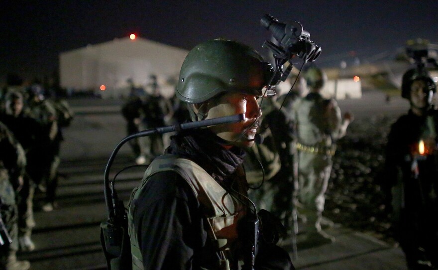 An Afghan commando stands on the tarmac, wearing night vision gear. The elite commandos are about to fly into an area controlled by Taliban fighters. Their mission: to sweep a village for Taliban fighters.