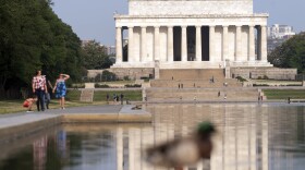 With a blue sky above the Lincoln Memorial, people walk along the reflection pool in Washington, D.C., on June 9, 2023.