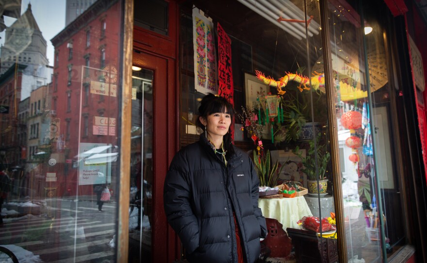 Mei Lum, the fifth generation owner of Wing on Wo porcelain shop, watches the festivities outside the store in Chinatown.