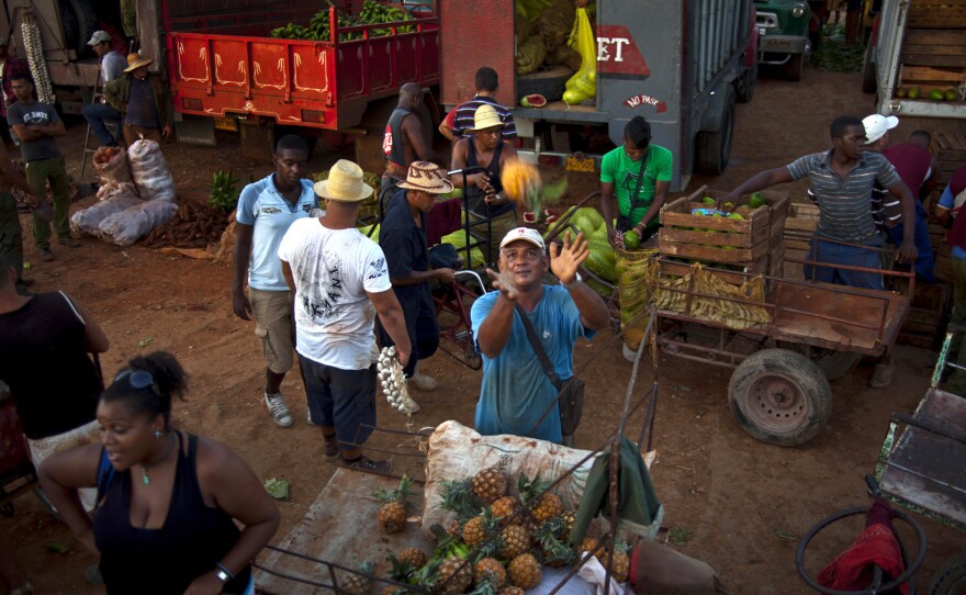 A vendor reaches out to catch a pineapple at a food market in the outskirts of Havana, Cuba, Sept. 25, 2013.