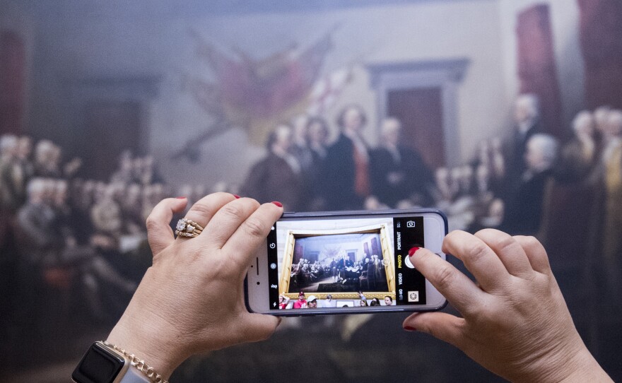 A tourist takes a photo of John Trumbull's Declaration of Independence painting in the Capitol Rotunda on June 28, 2017.