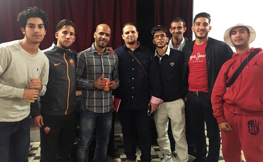 Mourad Benchellali (center, in all black) stands with teenagers after a talk about how to avoid being lured into a radical Islamist group. Standing to Benchellali's right is social worker Hamad Ouanoufi, who works with high-risk youths.