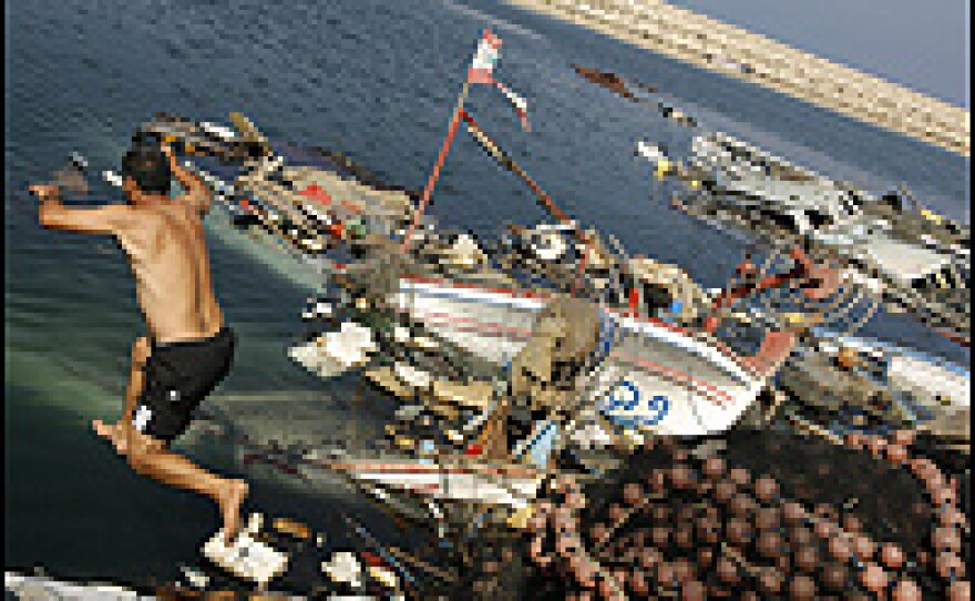 A Lebanese fisherman jumps into the water to retrieve his fishing materials at the port in Beirut's Uzai district, a day after Israeli airstrikes.