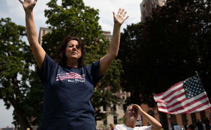 Sharon Lofquist raises her arms to religious music as demonstrators gathered to protest vaccine mandates outside the Michigan State Capitol in Lansing in August.
