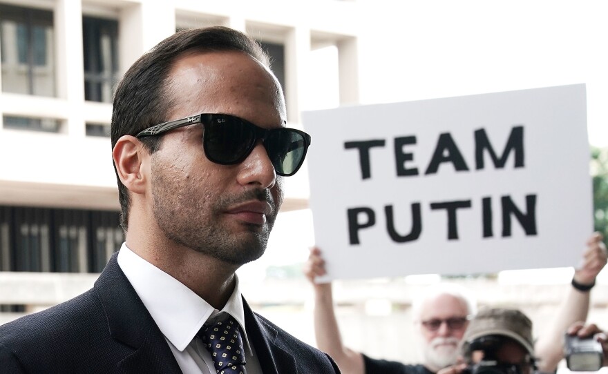A protester holds up a sign as former Trump campaign aide George Papadopoulos arrives at the U.S. District Court for his sentencing hearing Friday in Washington, D.C.